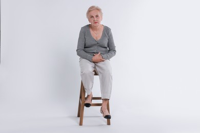 Photo of Senior woman on chair against white background