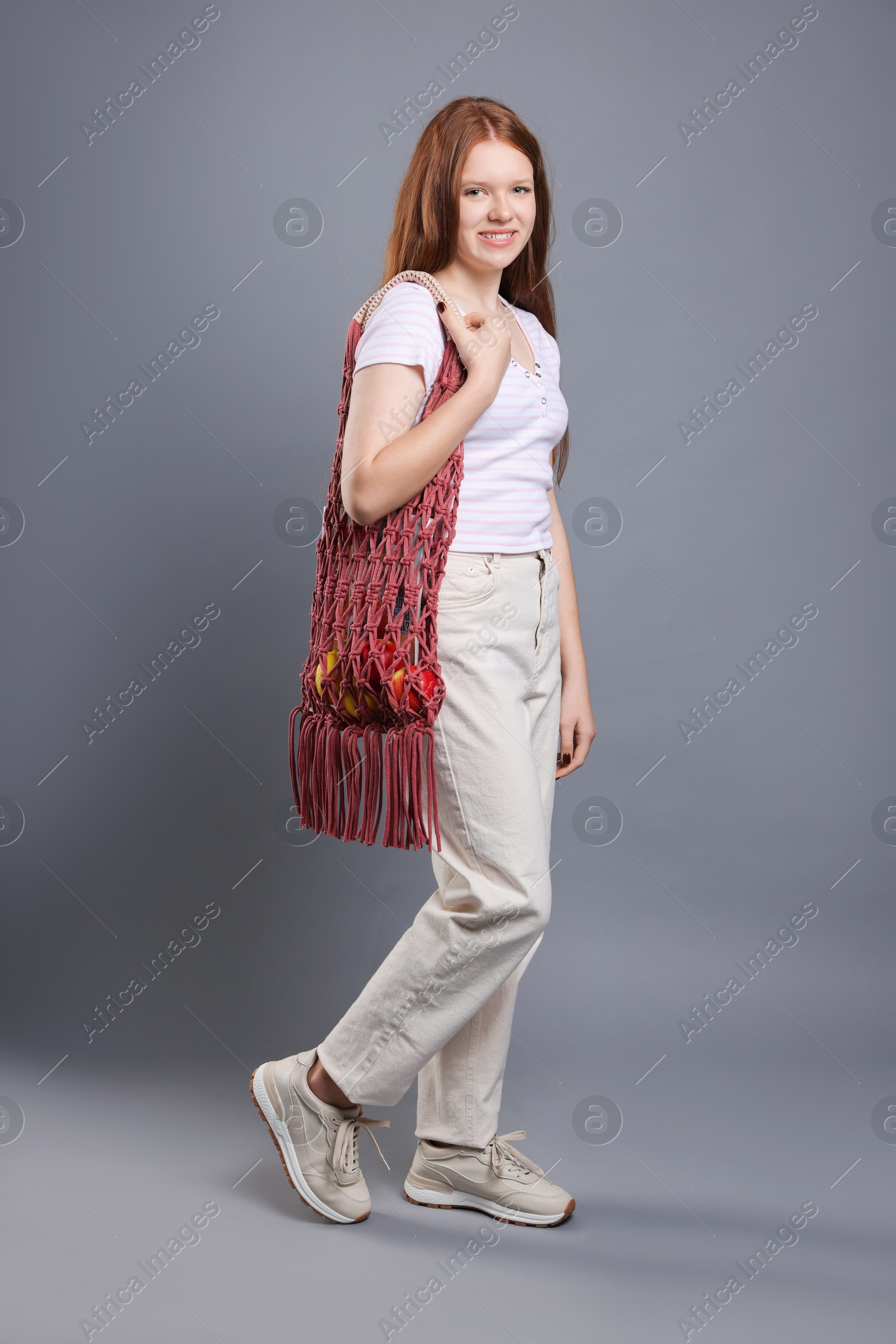 Photo of Teenage girl with handmade macrame bag on grey background