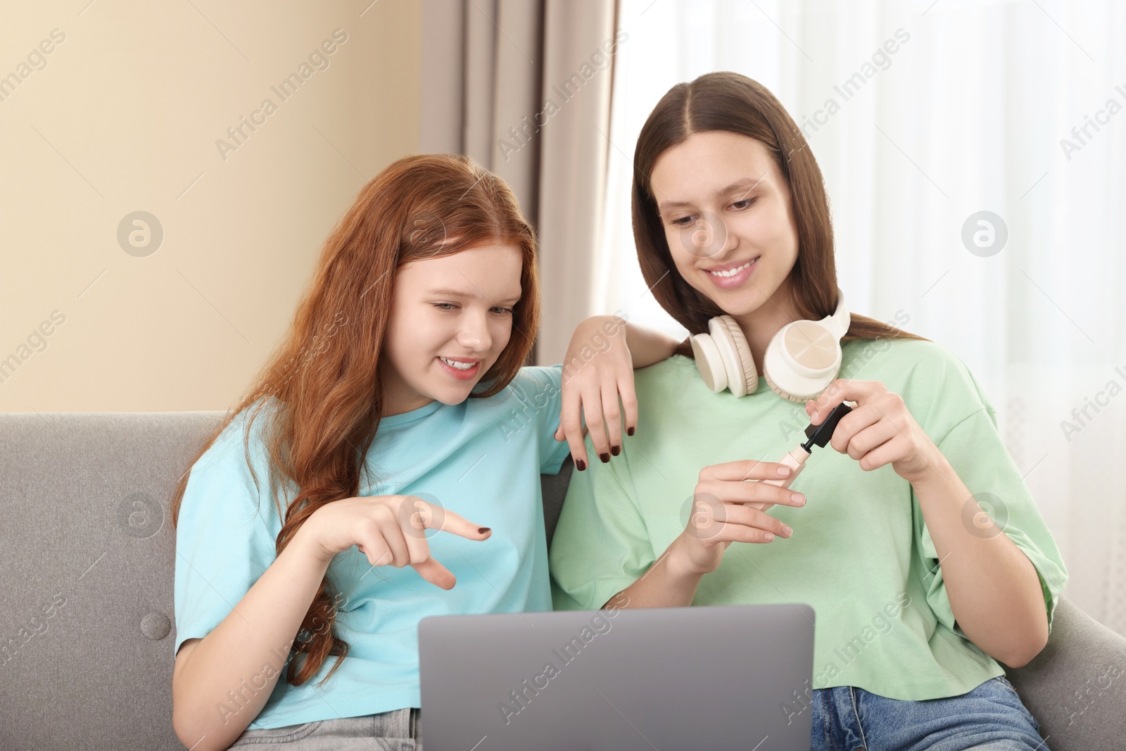 Photo of Teenage girls with laptop applying makeup products indoors