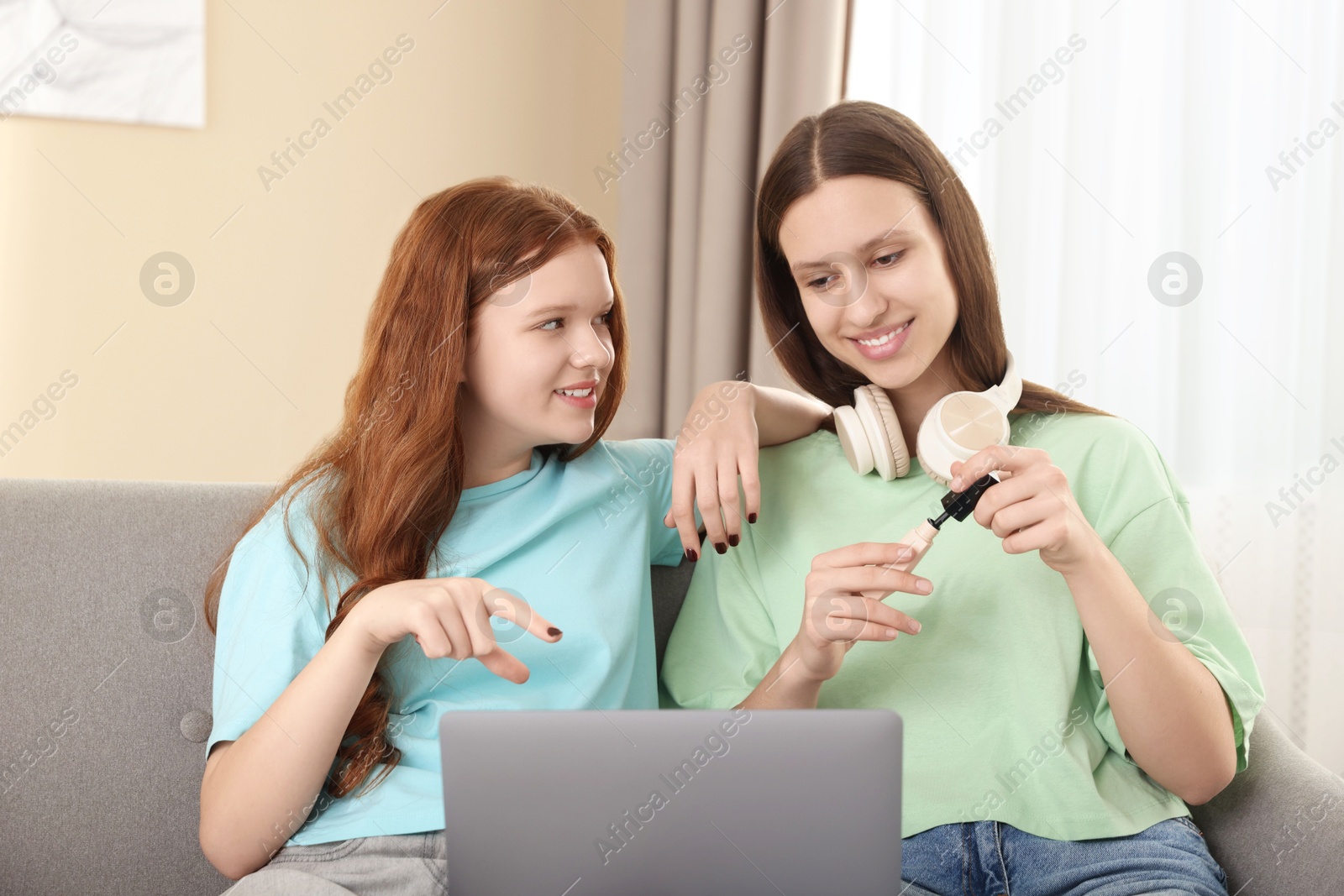 Photo of Teenage girls with laptop applying makeup products indoors