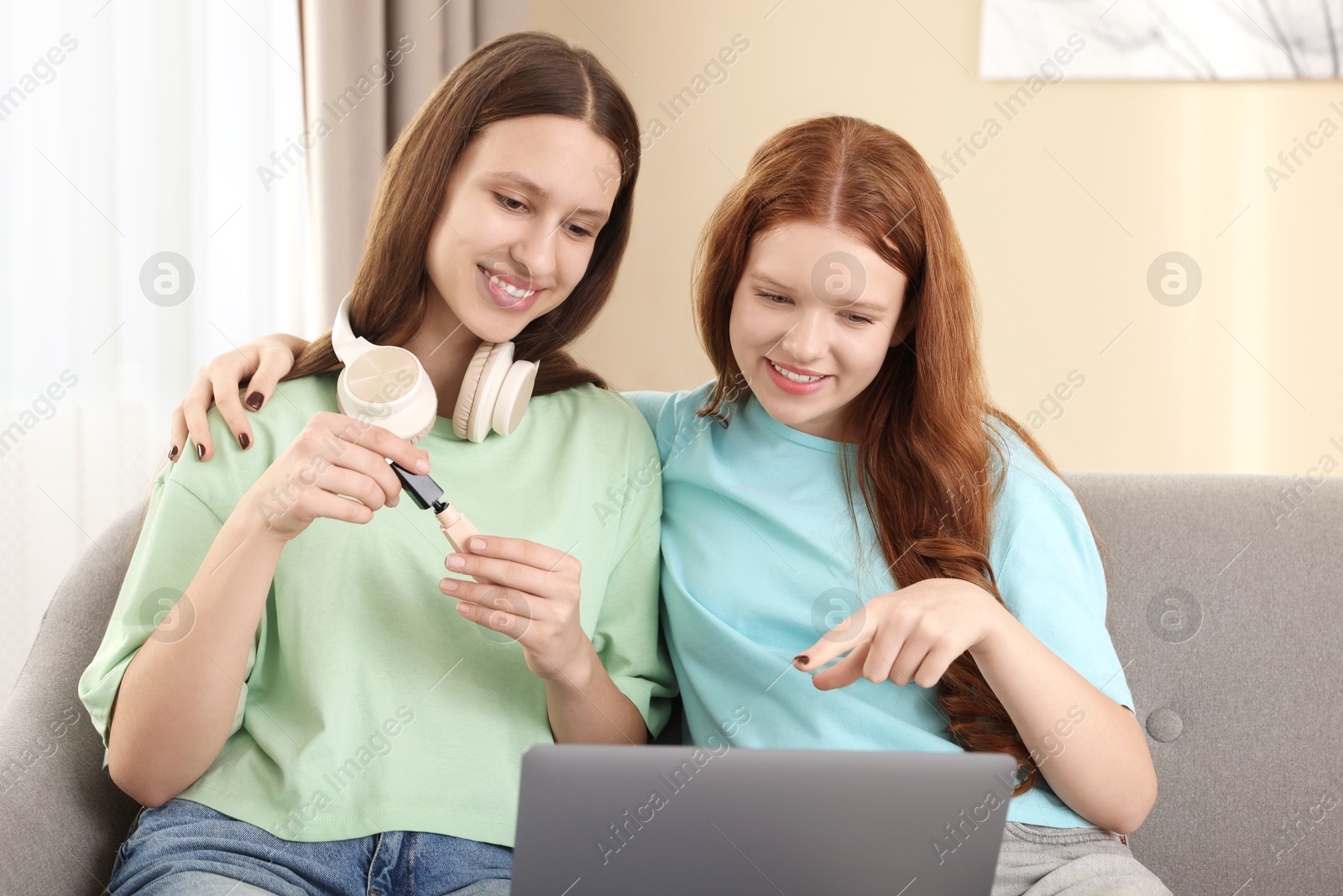 Photo of Teenage girls with laptop applying makeup products indoors