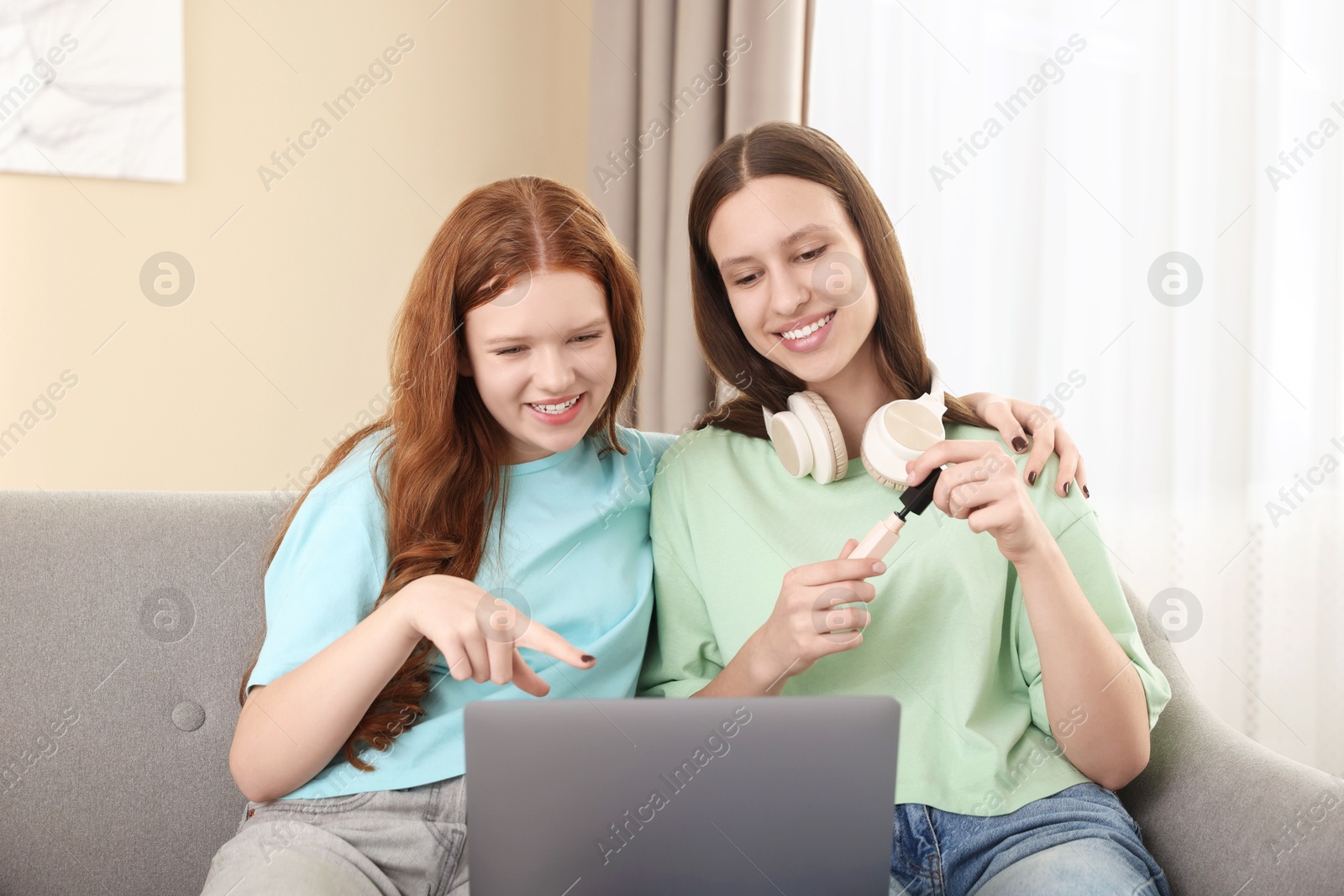 Photo of Teenage girls with laptop applying makeup products indoors