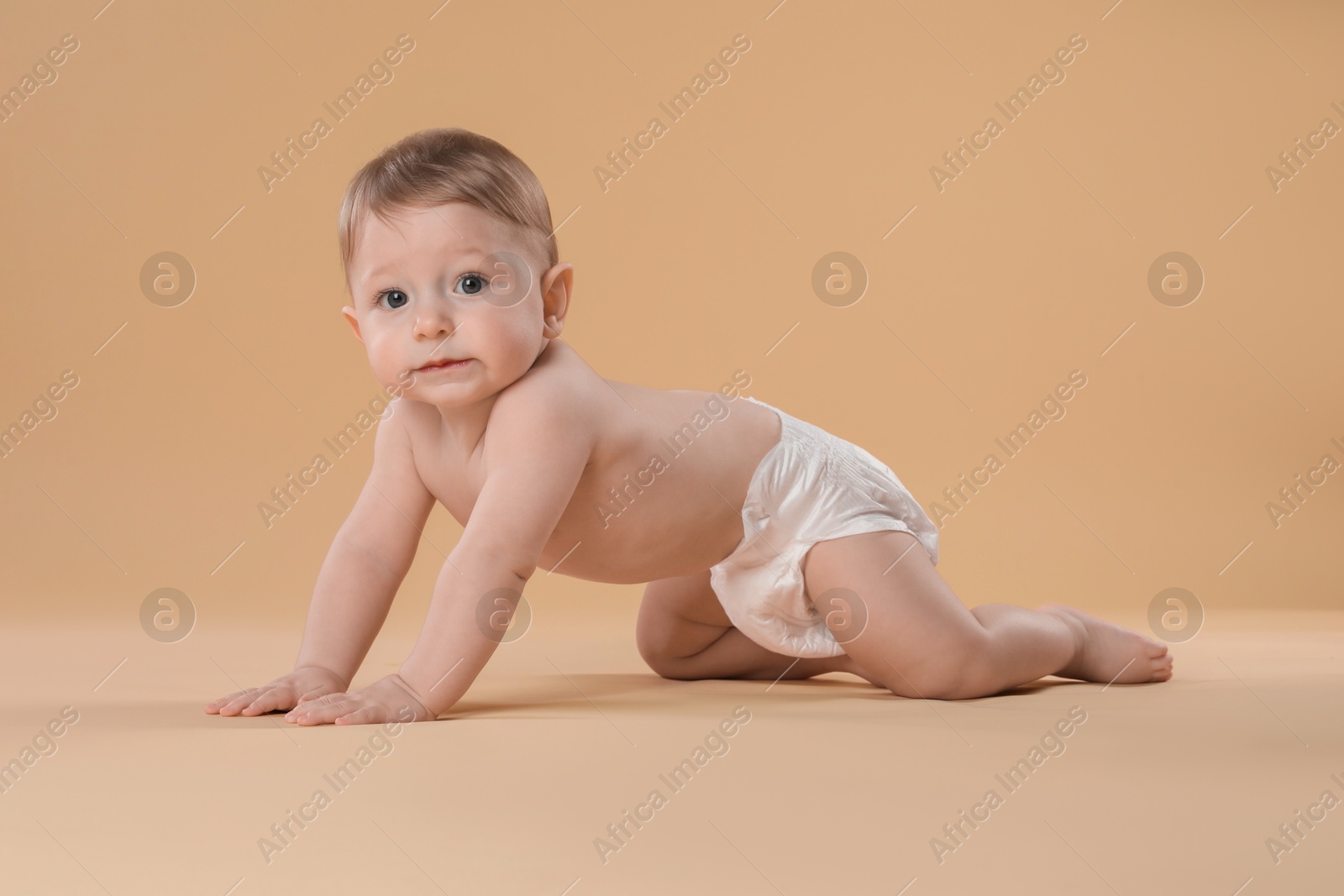 Photo of Cute little baby in diaper crawling on beige background