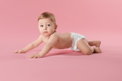 Photo of Cute little baby in diaper crawling on pink background