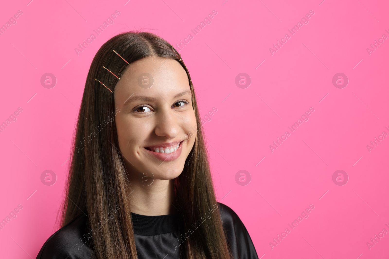 Photo of Teenage girl with stylish hair clips on pink background, space for text