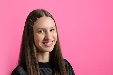 Photo of Teenage girl with stylish hair clips on pink background, space for text