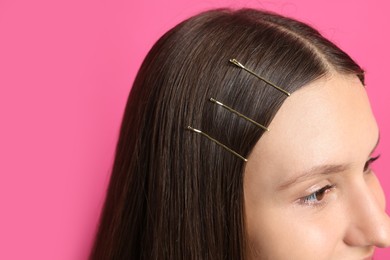 Photo of Teenage girl with stylish hair clips on pink background, closeup