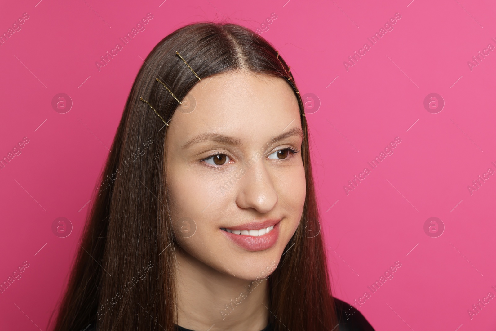 Photo of Teenage girl with stylish hair clips on pink background