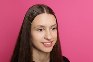 Teenage girl with stylish hair clips on pink background