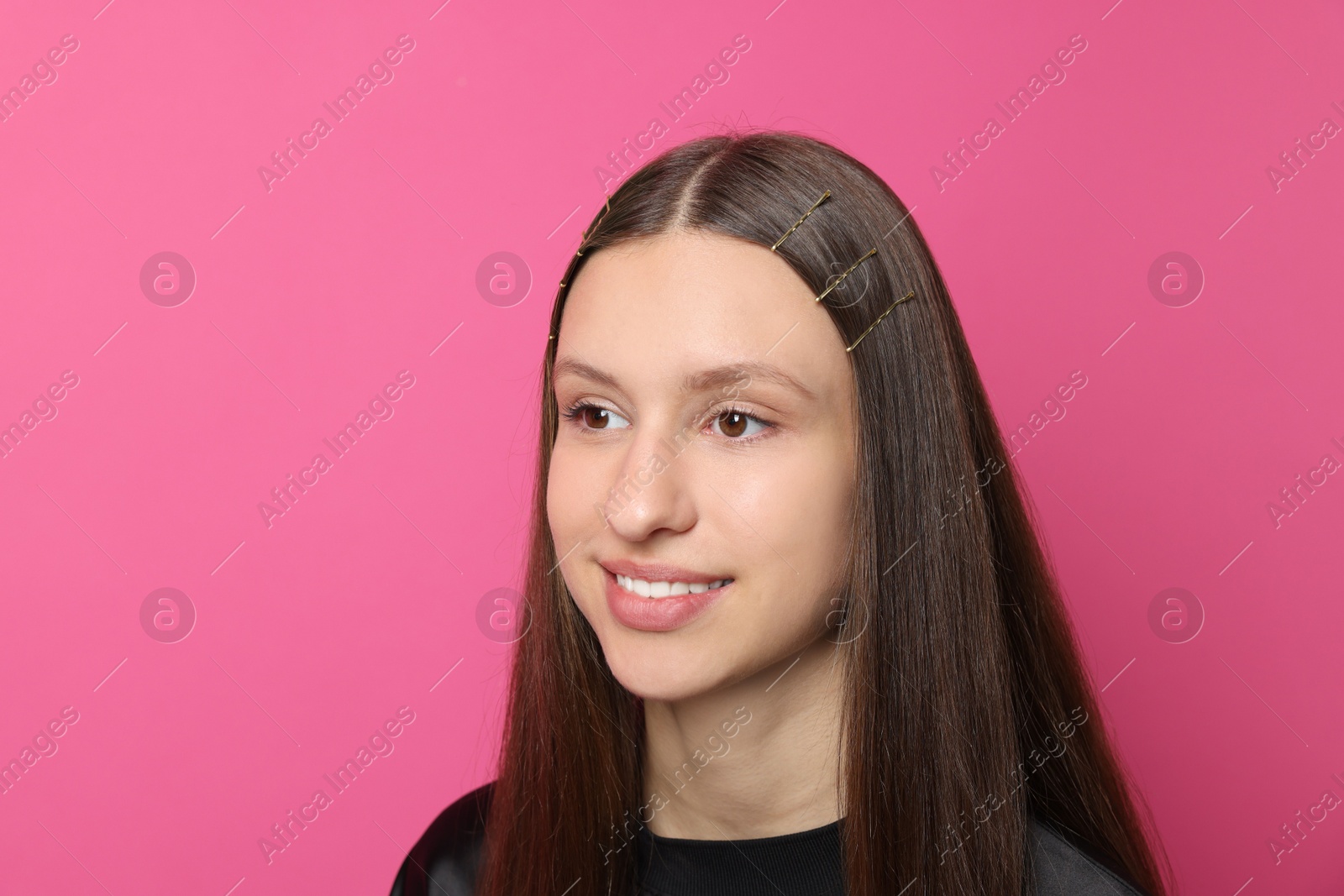 Photo of Teenage girl with stylish hair clips on pink background