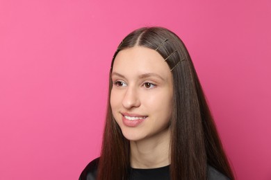 Photo of Teenage girl with stylish hair clips on pink background