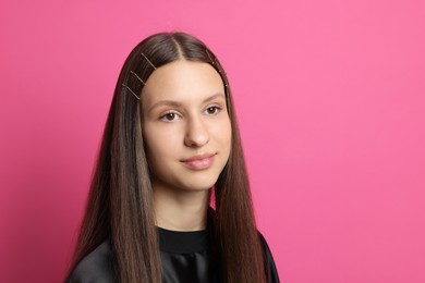 Teenage girl with stylish hair clips on pink background