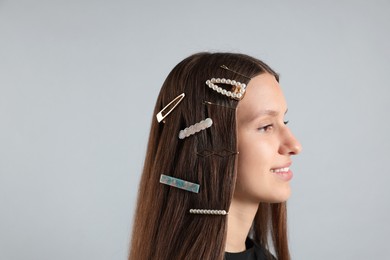 Photo of Teenage girl with stylish hair clips on light grey background, closeup