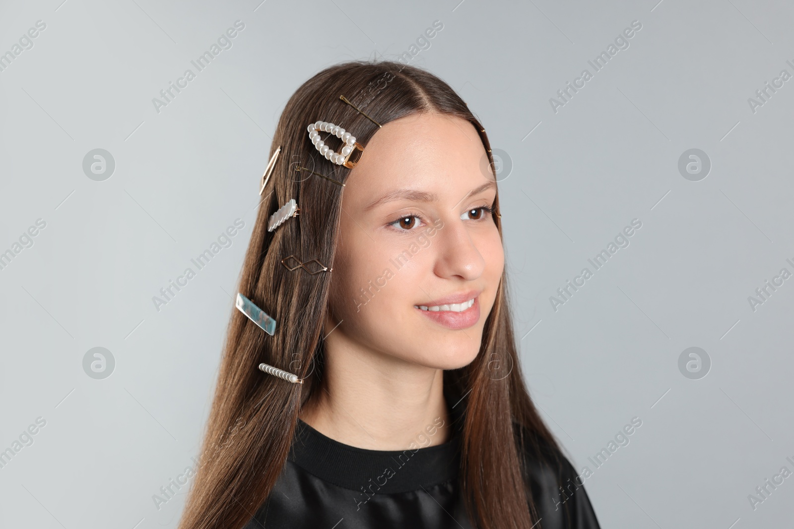 Photo of Teenage girl with stylish hair clips on light grey background, closeup