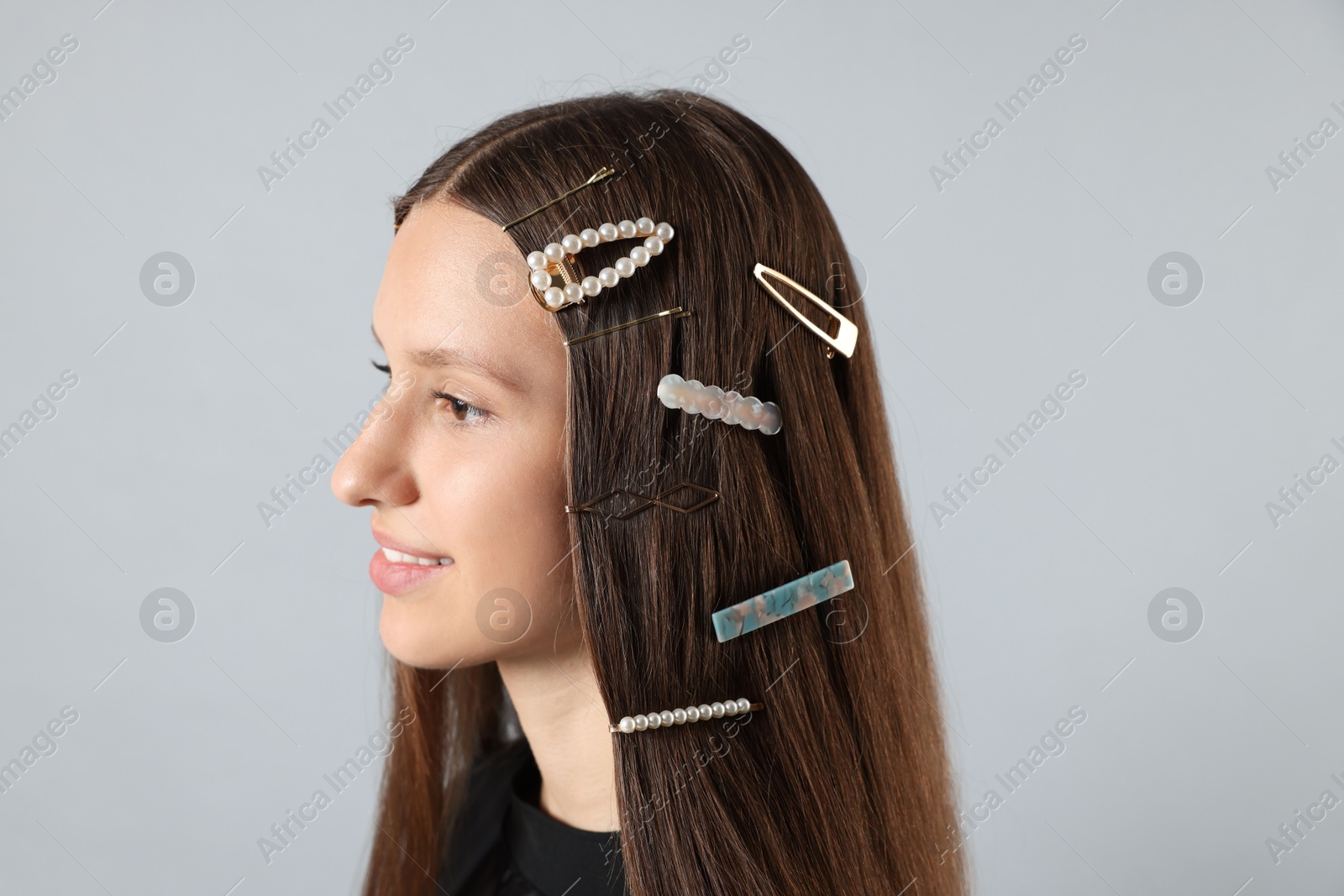 Photo of Teenage girl with stylish hair clips on light grey background, closeup