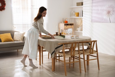 Photo of Woman setting table for dinner at home