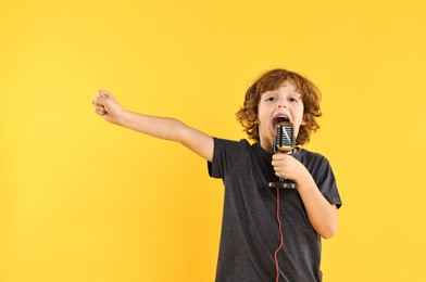 Photo of Little boy with microphone singing on yellow background