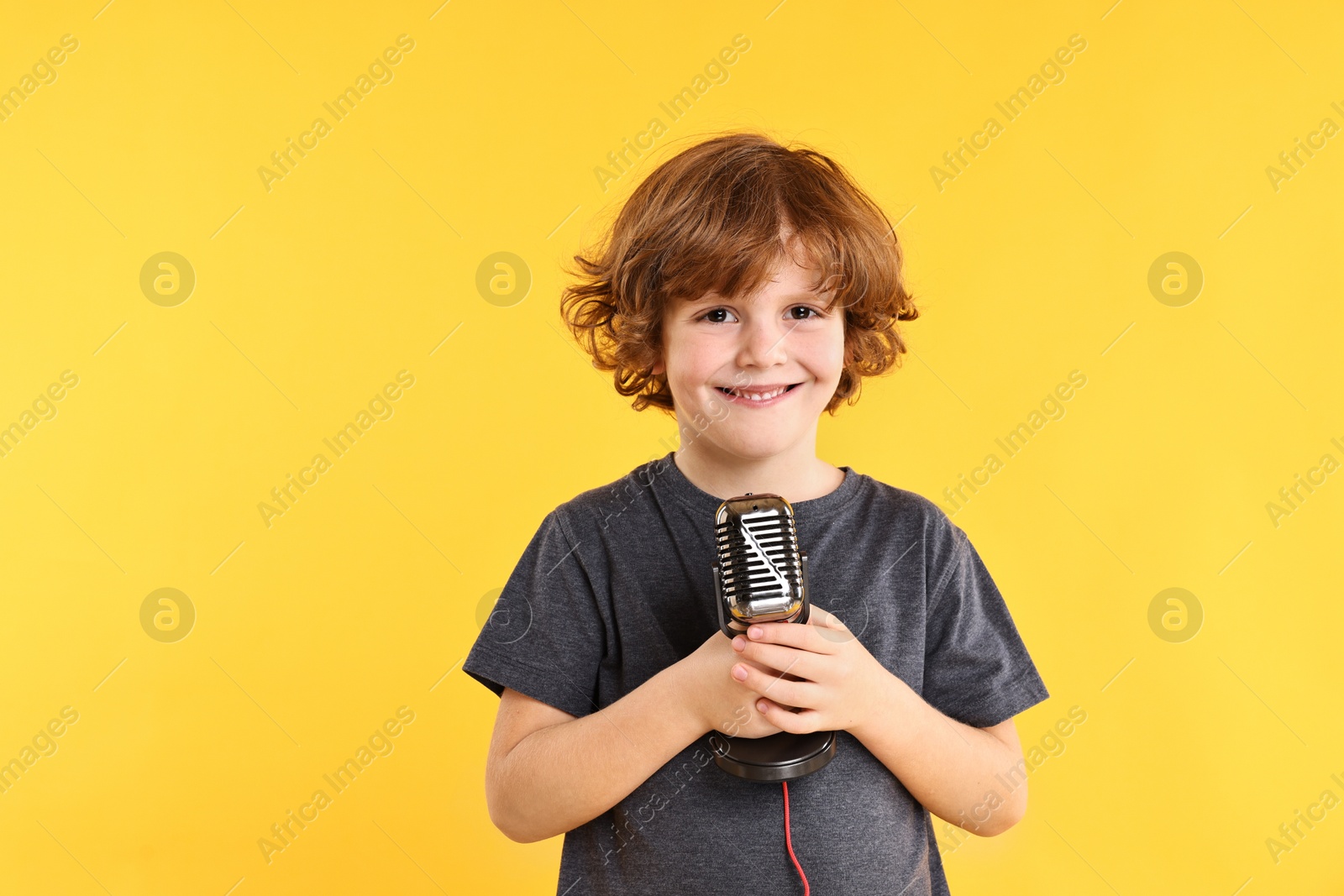 Photo of Little boy with microphone on yellow background