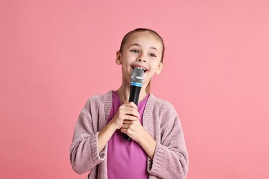 Photo of Little girl with microphone singing on pink background