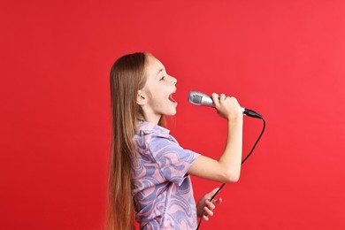 Photo of Little girl with microphone singing on red background