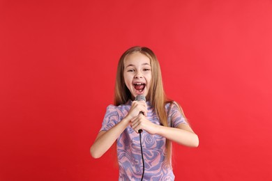 Photo of Little girl with microphone singing on red background