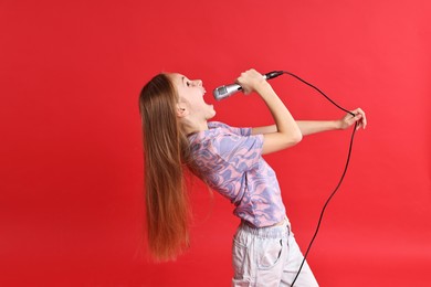 Photo of Little girl with microphone singing on red background