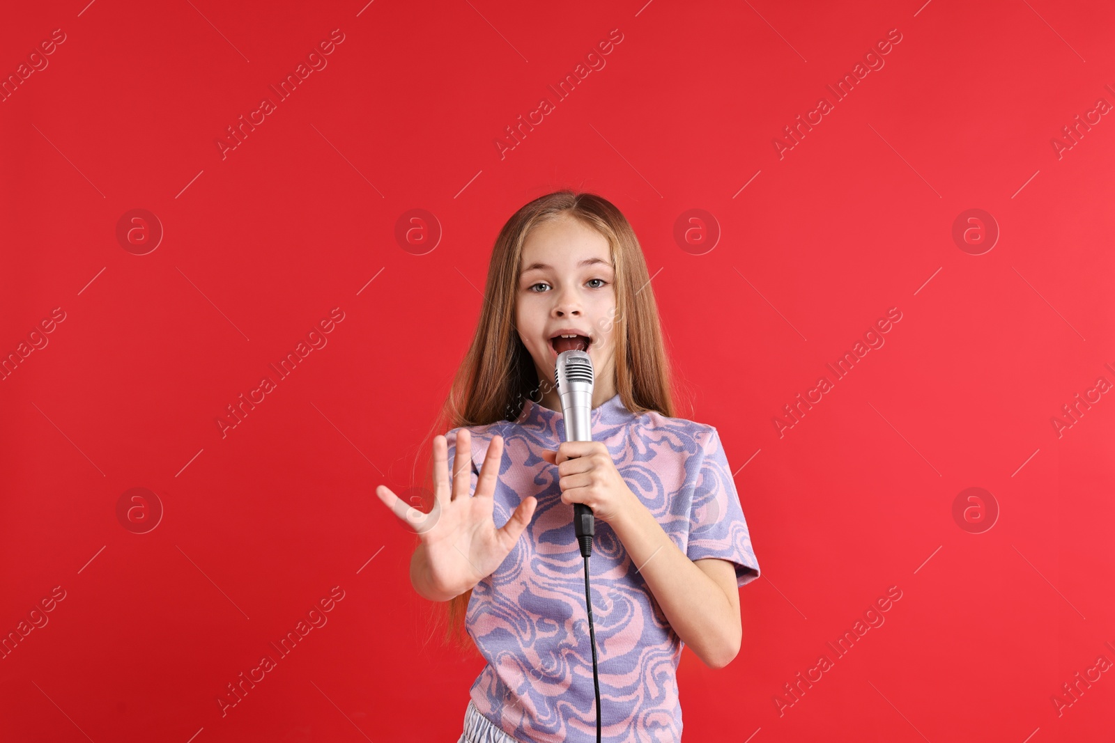 Photo of Little girl with microphone singing on red background