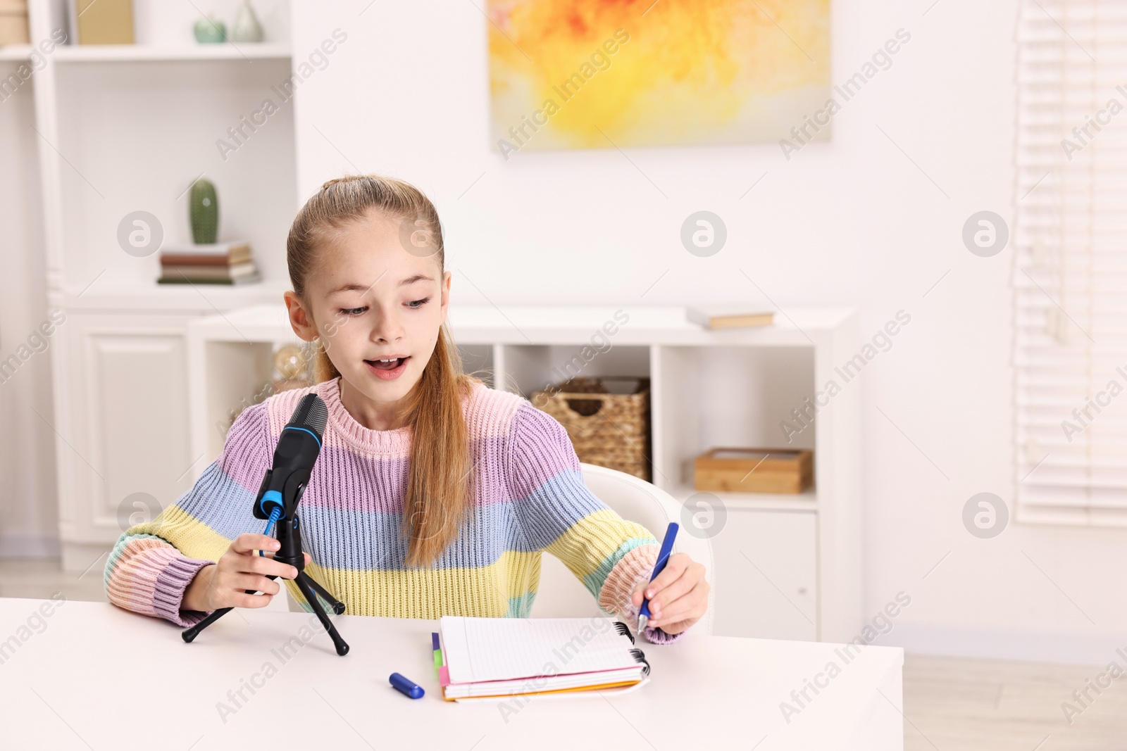 Photo of Little girl with microphone at white table indoors, space for text