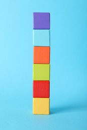 Photo of Colorful wooden cubes on light blue background