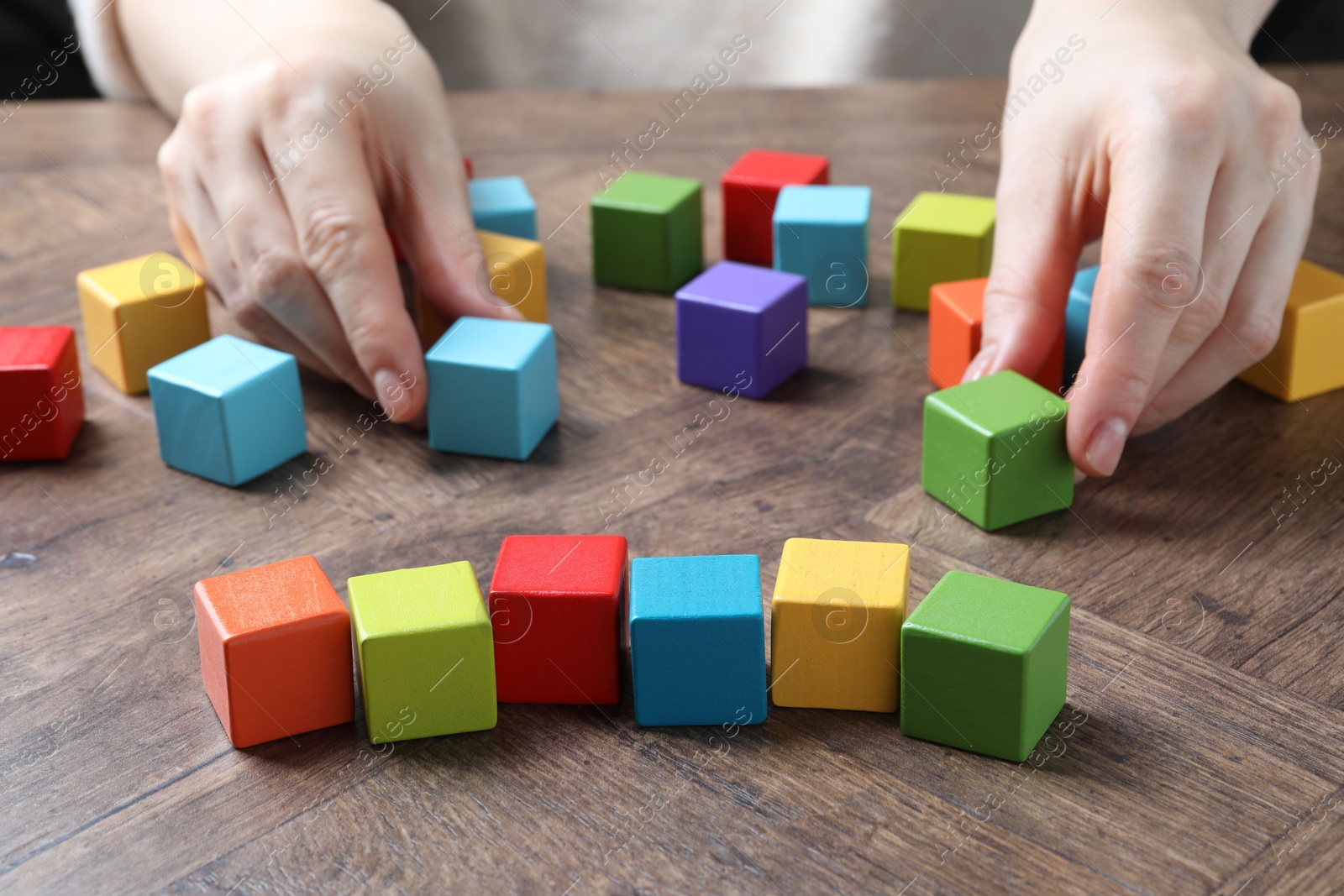 Photo of Woman with colorful cubes at wooden table, closeup