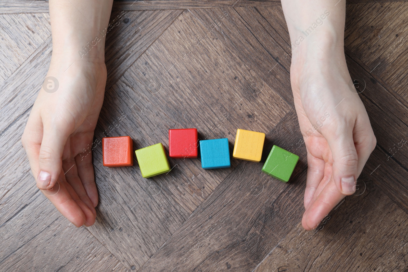 Photo of Woman with colorful cubes at wooden table, top view