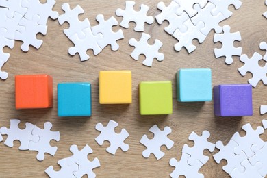 Photo of Colorful cubes and puzzle pieces on wooden background, flat lay