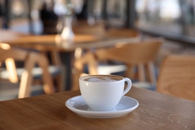 Photo of Cup of aromatic coffee on wooden table in cafe, closeup. Space for text