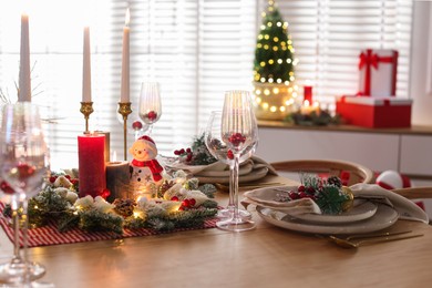 Photo of Christmas place setting with festive decor on wooden table in room