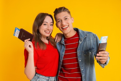 Happy travellers with passports and tickets on yellow background