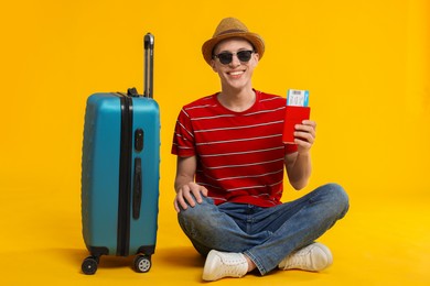 Photo of Happy traveller with suitcase, passport and ticket on yellow background