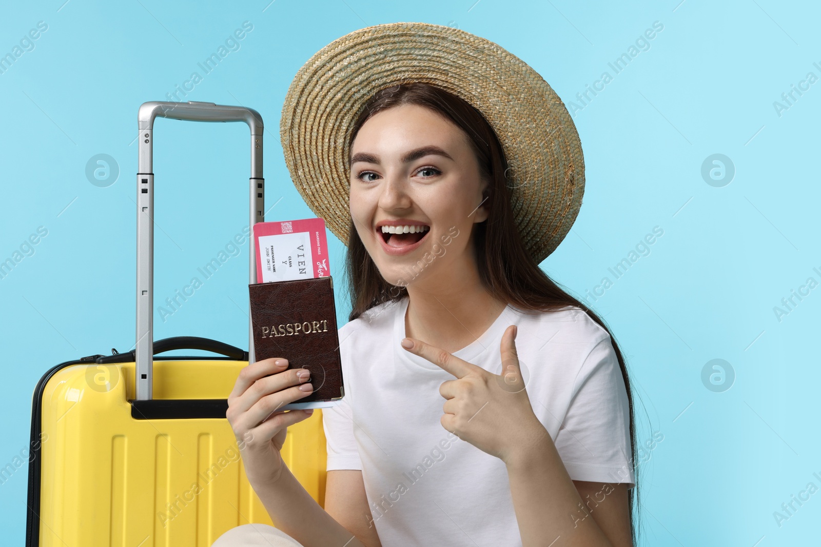 Photo of Woman with ticket, passport and suitcase on light blue background