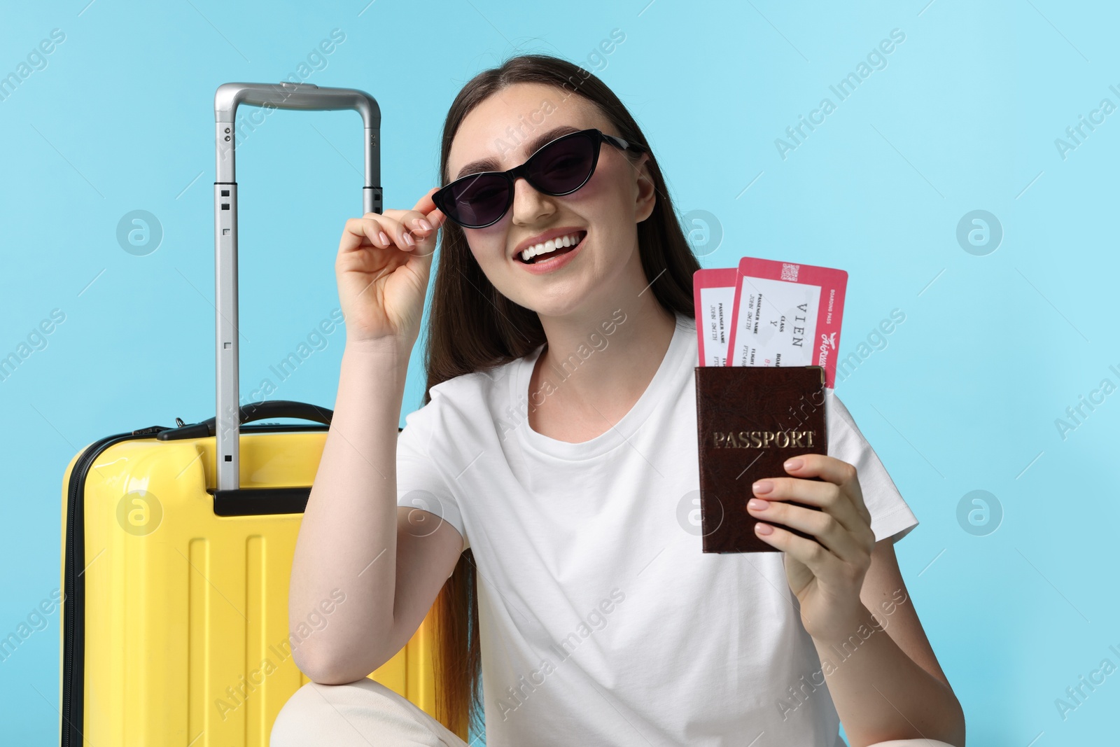 Photo of Woman with tickets, passport and suitcase on light blue background