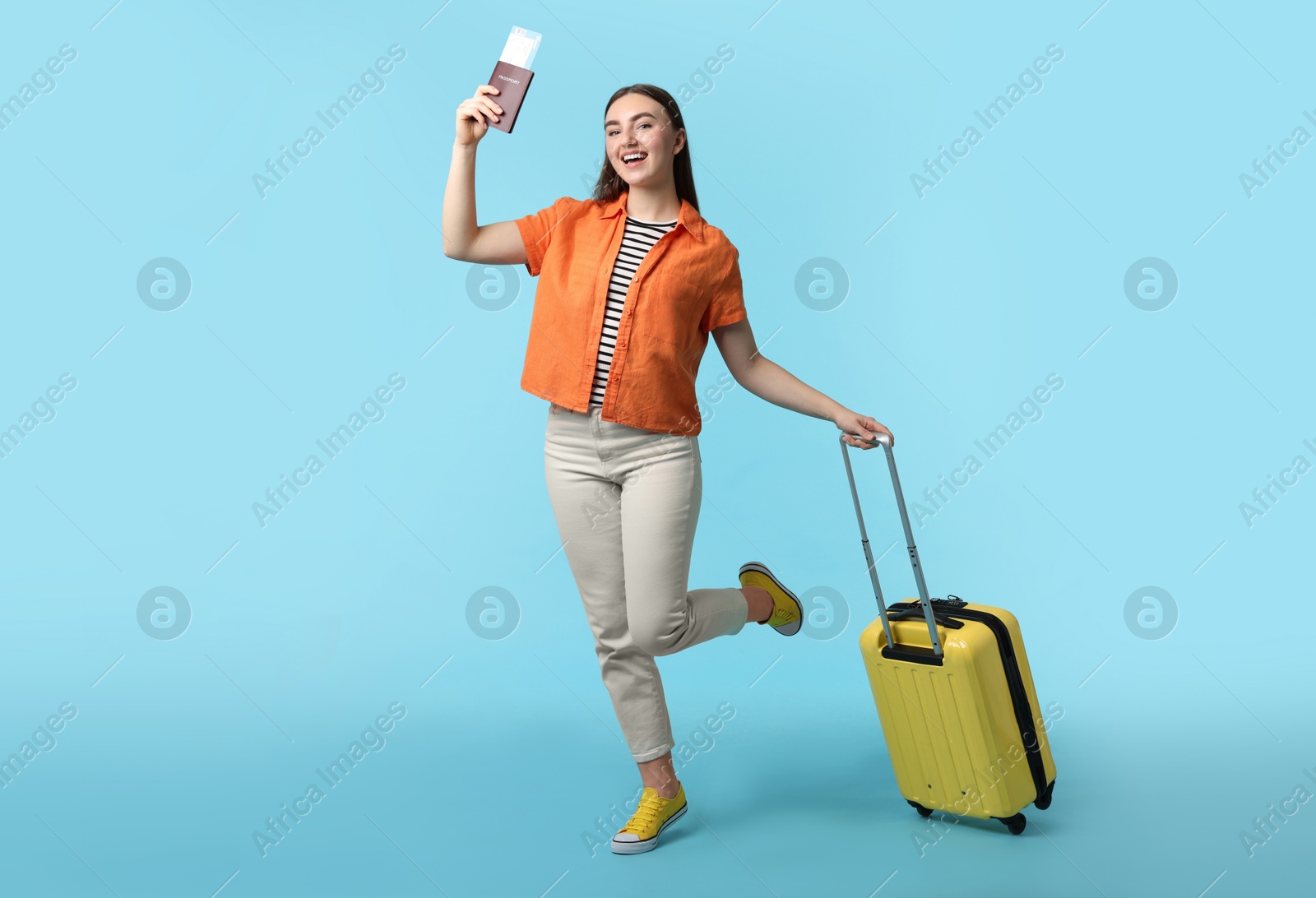 Photo of Woman with ticket, passport, and suitcase on light blue background