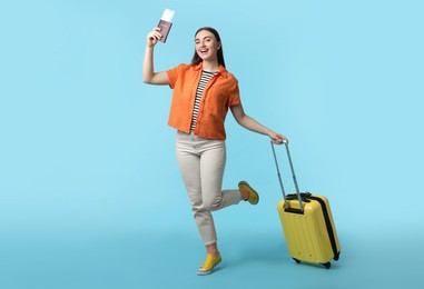 Woman with ticket, passport, and suitcase on light blue background