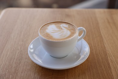 Photo of Cup of aromatic coffee on wooden table in cafe, closeup