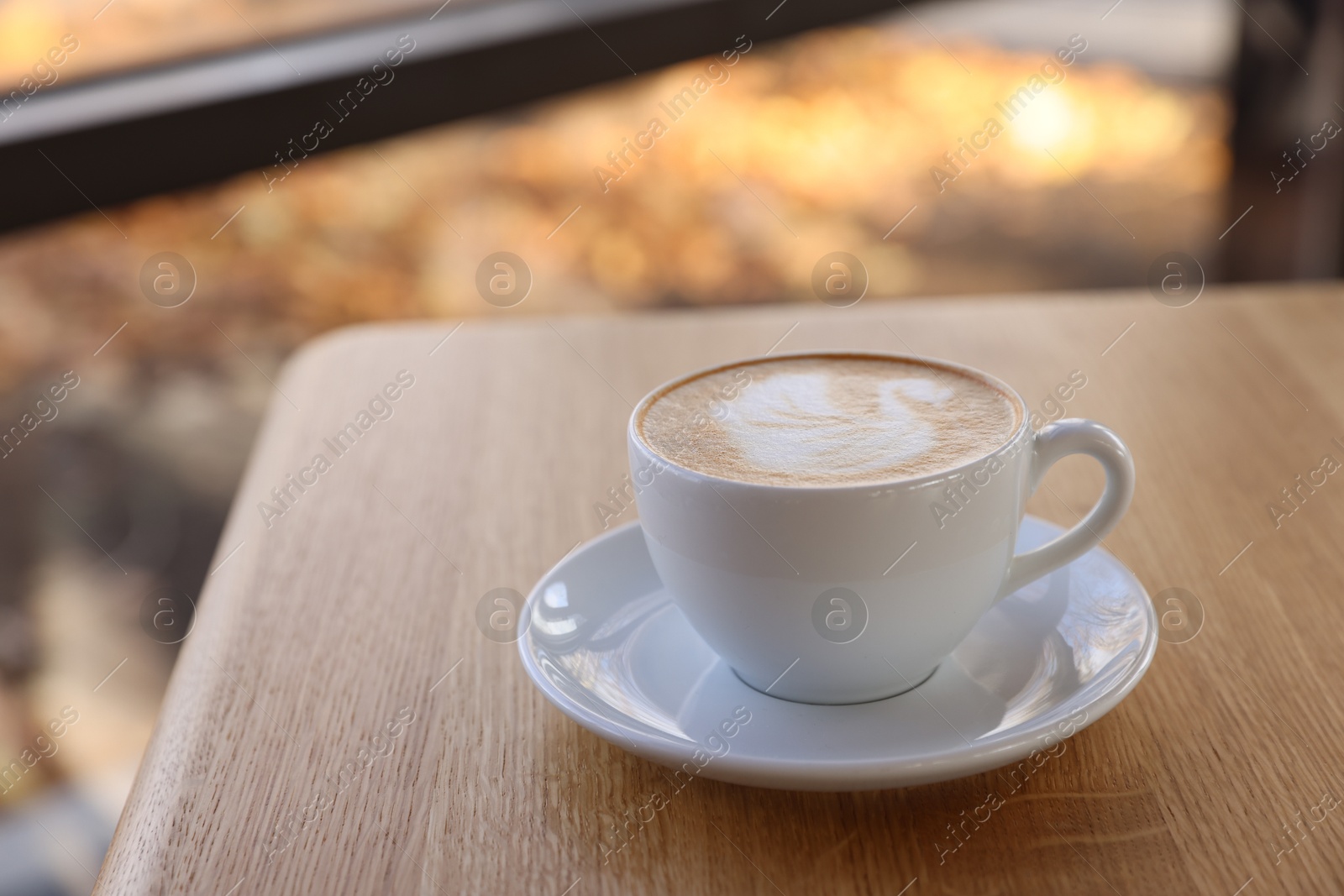 Photo of Cup of aromatic coffee on wooden table in cafe, closeup. Space for text