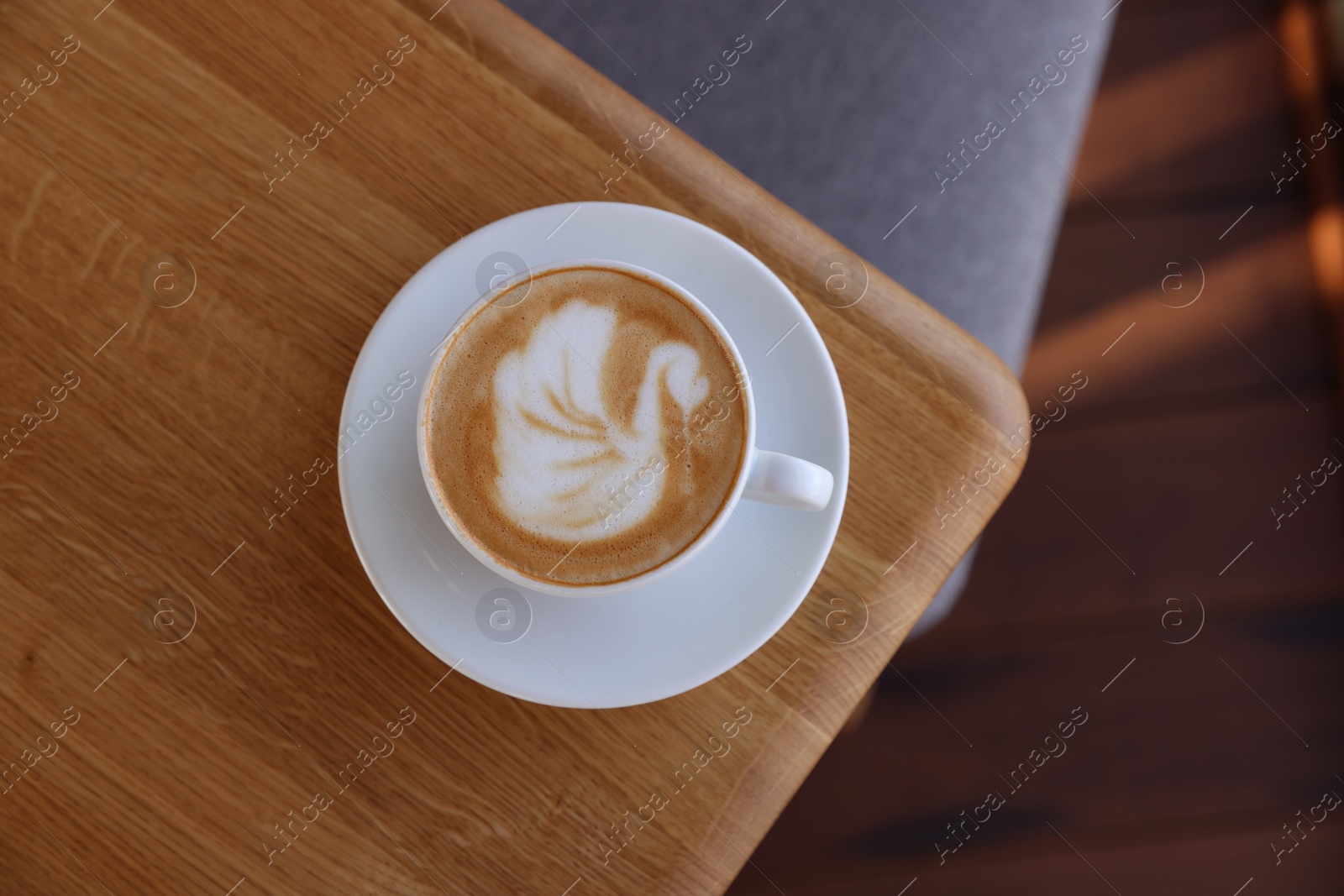 Photo of Cup of aromatic coffee on wooden table in cafe, top view