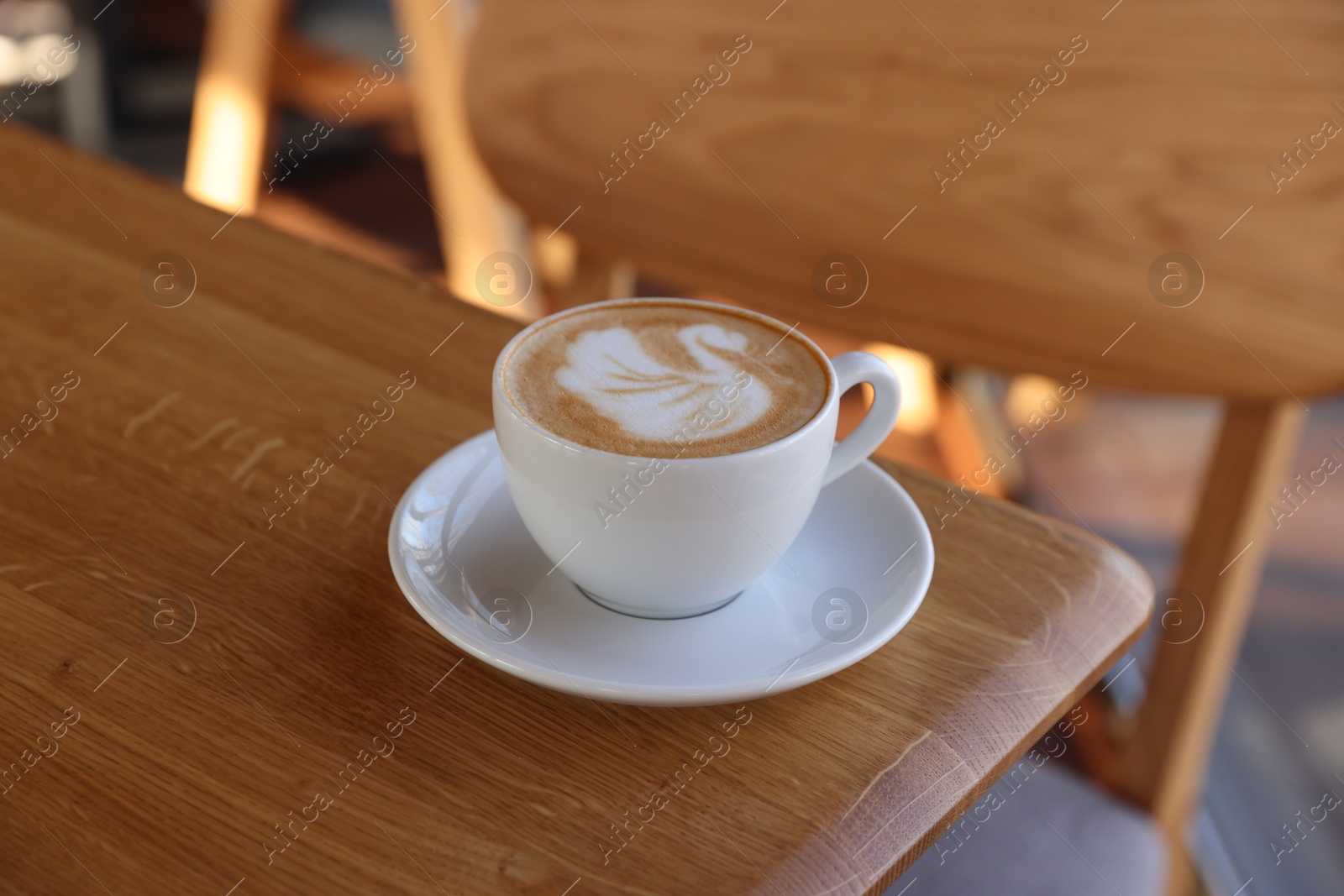 Photo of Cup of aromatic coffee on wooden table in cafe, closeup