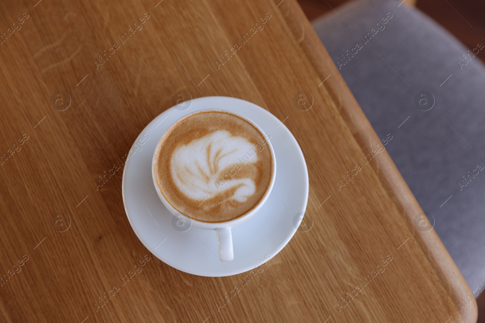 Photo of Cup of aromatic coffee on wooden table in cafe, top view