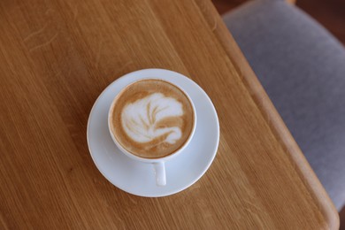 Photo of Cup of aromatic coffee on wooden table in cafe, top view