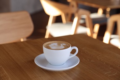 Photo of Cup of aromatic coffee on wooden table in cafe