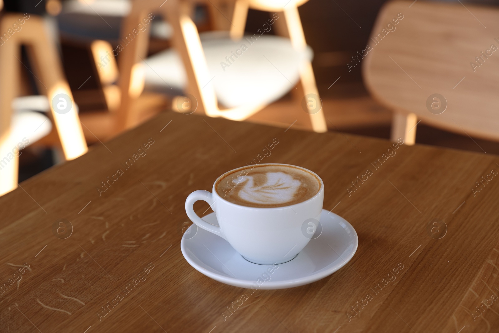 Photo of Cup of aromatic coffee on wooden table in cafe