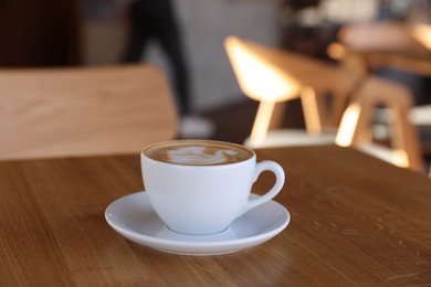 Photo of Cup of aromatic coffee on wooden table in cafe