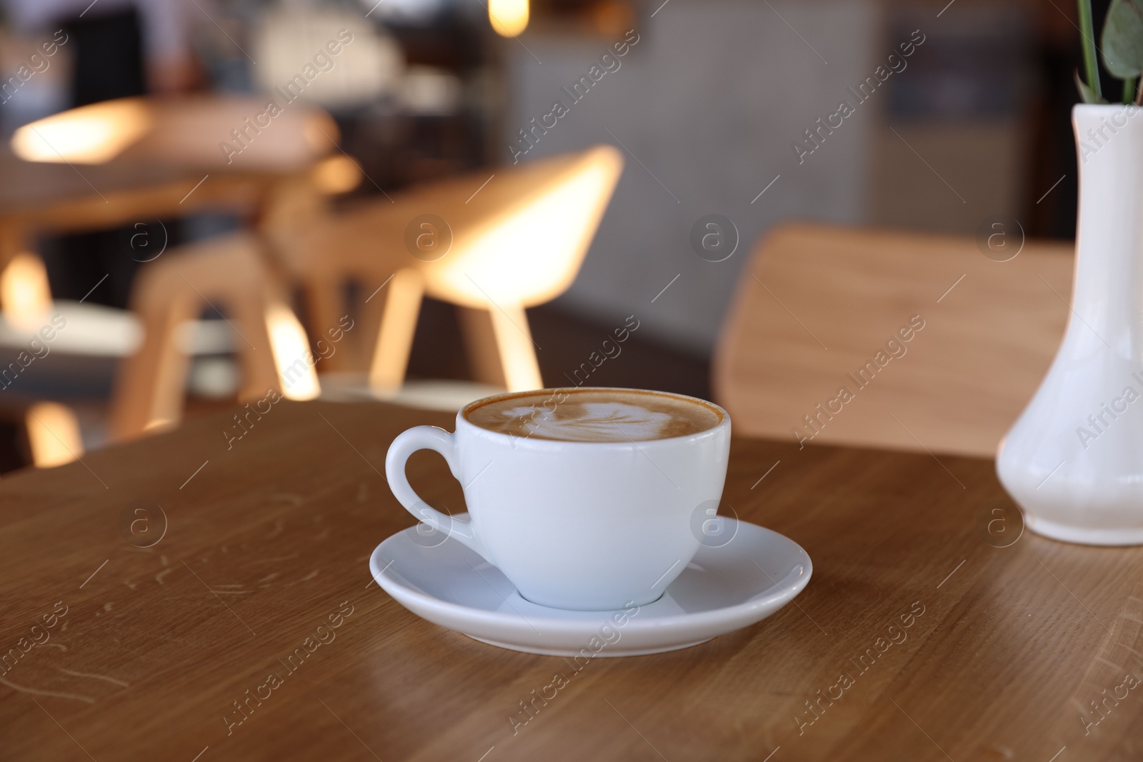 Photo of Cup of aromatic coffee on wooden table in cafe